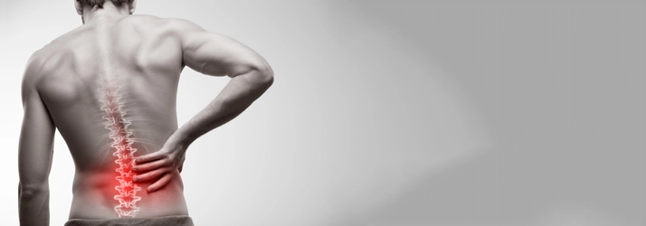 A man holding his lower back. His spine is highlighted red.