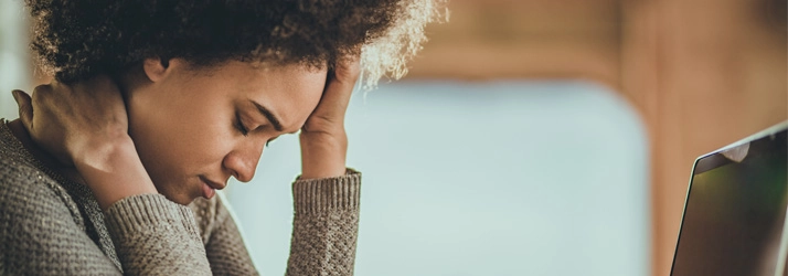 A woman holding her forehead.