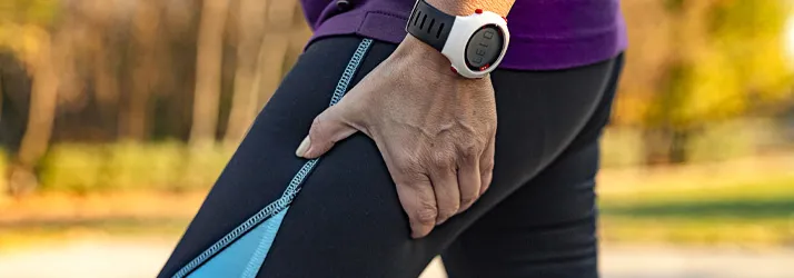 A person holding their upper thigh.